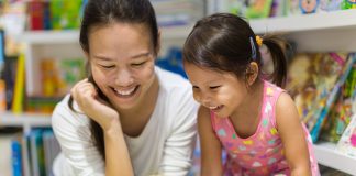 Parent and child reading books together in the library.