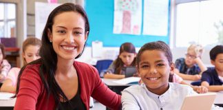 Portrait of teacher with elementary school teacher at his desk